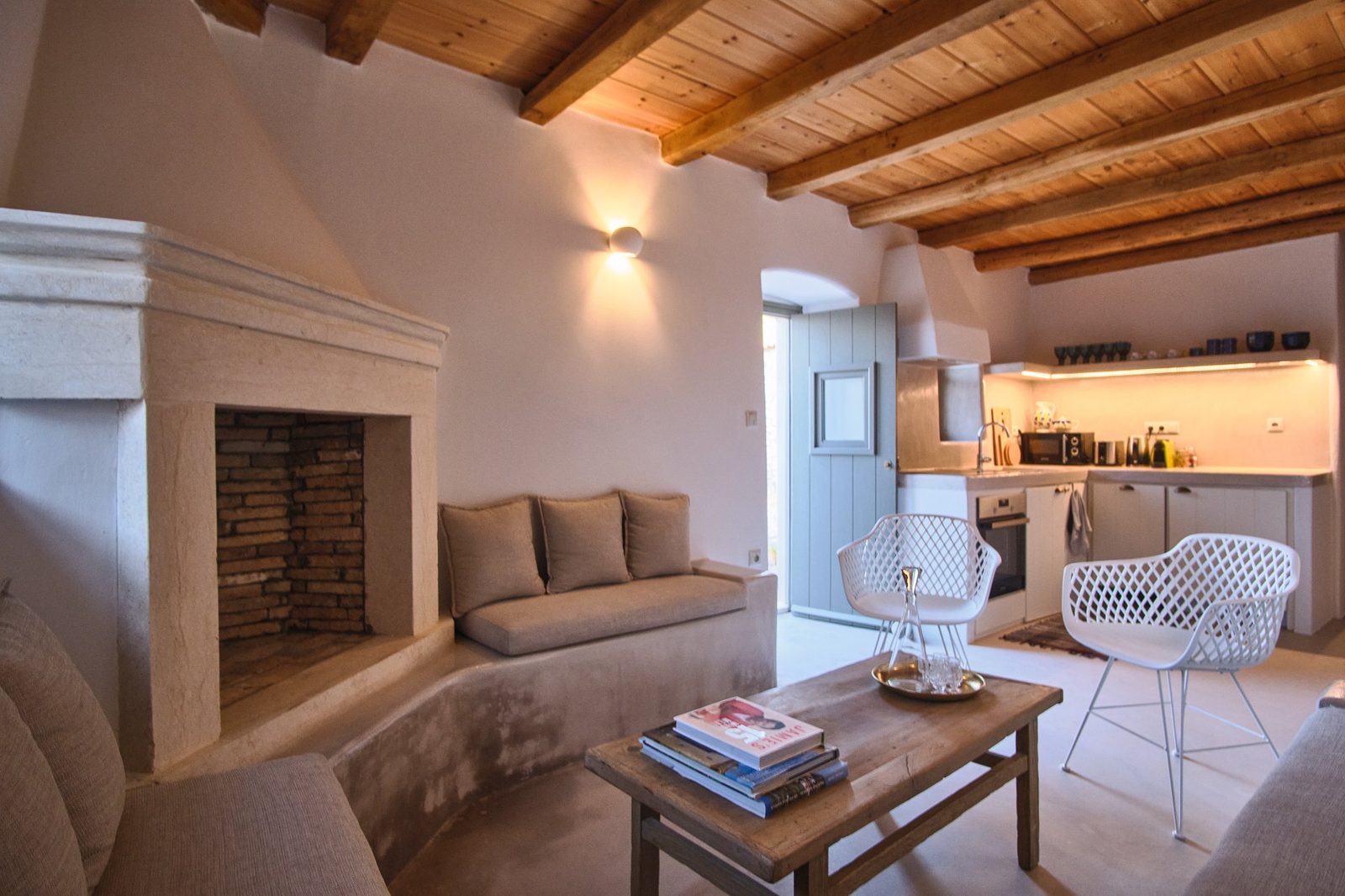Living room with stone fireplace, built-in sofas, and timber ceiling beams